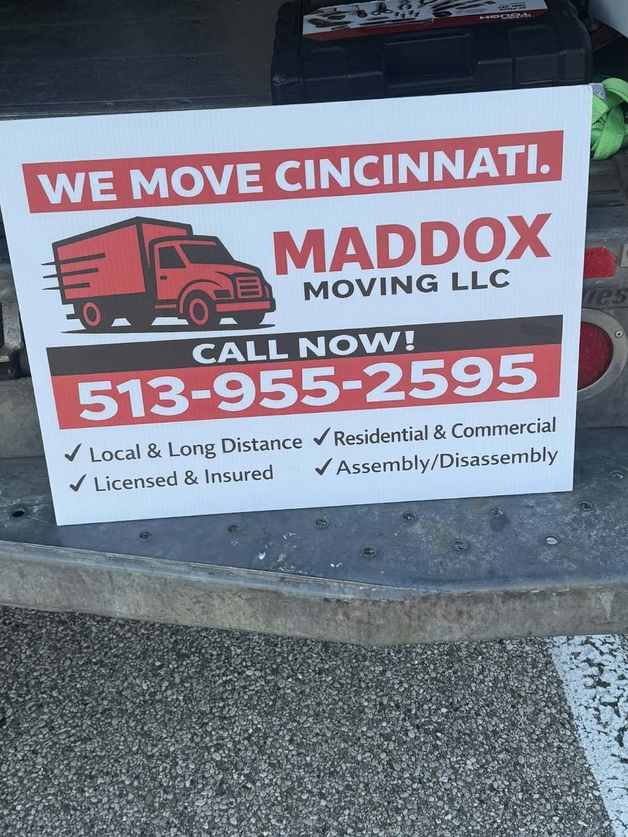 A white Maddox Moving LLC yard sign leaning on a truck bumper, with a red truck logo, the words We Move Cincinnati and the phone number 513-955-2595.